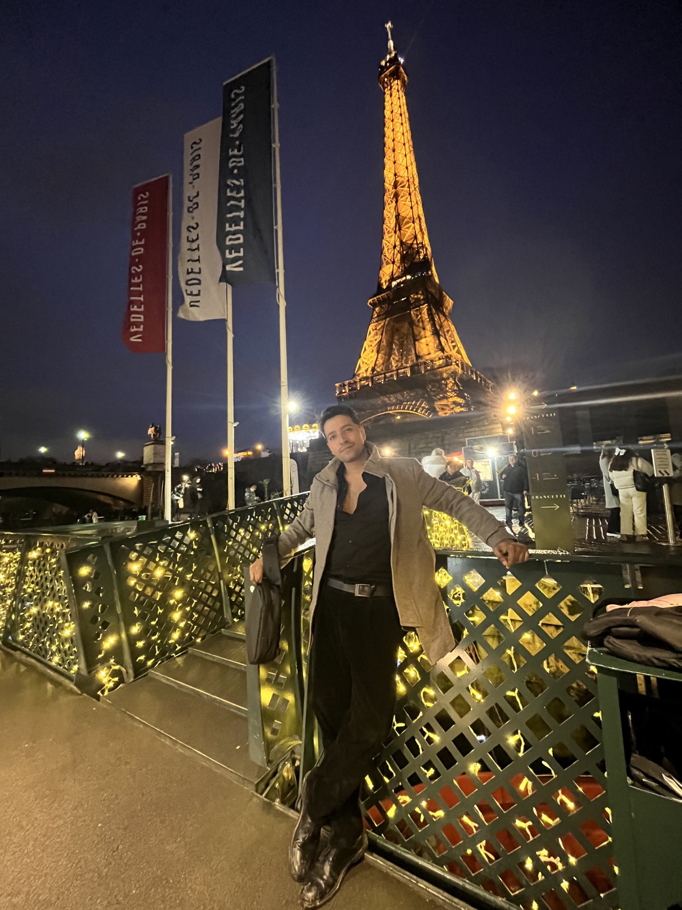 Pradip beneath the illuminated Eiffel Tower